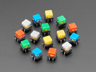 Angled  shot of 15 colorful square tactile button switches in green, yellow, red, blue, and white.