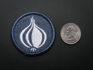 Circular embroidered badge of stylized onion Perl logo in white, on a greyish blue background. 