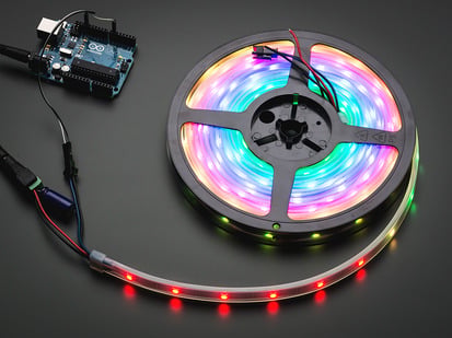 Adafruit NeoPixel Digital RGB LED Strip - White 30 LED - 5m - Adafruit NeoPixel Digital RGB LED Strip reel wired to a microcontroller, with all the LEDs in a rainbow