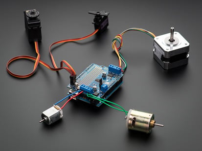 Adafruit Motor/Stepper/Servo Shield for Arduino v3 Kit - Angled shot of a Adafruit Motor/Stepper/Servo Shield for Arduino v2 Kit connected to several different steppers and servos. 