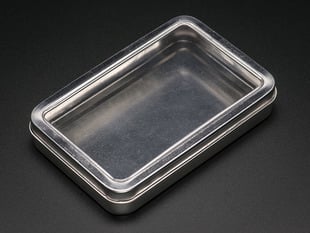Angled shot of 3.5" by 5.5" metal tin with a clear lid.