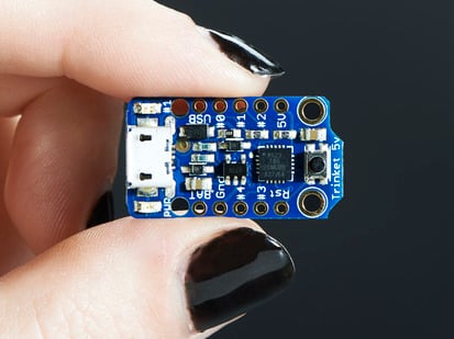 Adafruit Trinket - Mini Microcontroller - 5V Logic - Hand holding Adafruit TriHand holding small Adafruit Trinket - Mini Microcontrollerket board.
