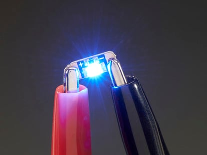 Adafruit LED Sequins - Royal Blue - Pack of 5 - Single LED sequin PCB attached to two alligator clips, glowing blue