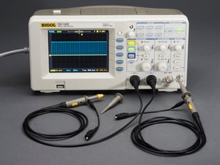 Oscilloscope powered on with probes.
