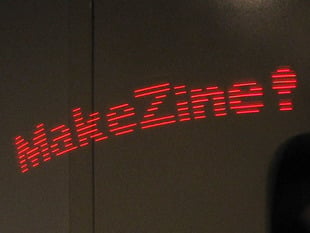Mini POV long-capture image showing "MakeZine!" in red lights.