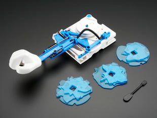 Angled shot of assembled Auto Writing Machine kit along with three blue plates and small hand tool.