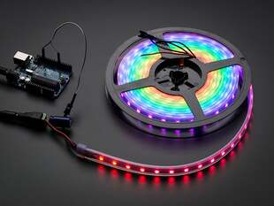 Angled shot of lit RGBW LED strip on a reel.