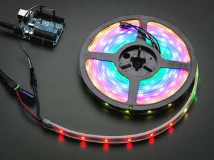 Powered on LED strip on a reel, emitting colored lights.