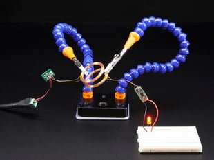 Demo Shot of the Mini Hand from Hobby Creek with Two Arms holding copper rings that are powering a red led.