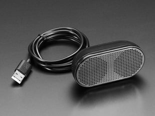 Small, black, oval USB speaker plugged with bundled cable.