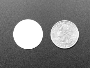 Overhead shot of small white disc next to US quarter for scale.