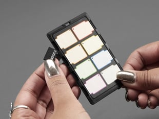 Two hands with a metallic manicure holding a black, rectangle-shaped micro SD card organizer.