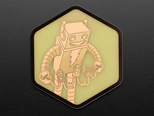 A PCB coaster featuring a friendly robot, AdaBot, and three LEDs.