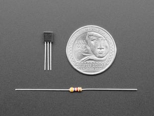 DS18B20 Digital temperature sensor next to a US quarter and above a resister. 