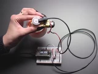 Demo Video of a Hand holding motor with spinning wheel. T-slot sensor is attached over an encoder disk and is showing the RPM on an OLED display