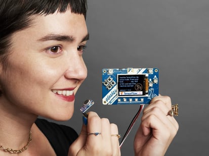 TensorFlow Lite for Microcontrollers Kit - Female holding an a assembled TensorFlow Lite for Microcontrollers Kit.