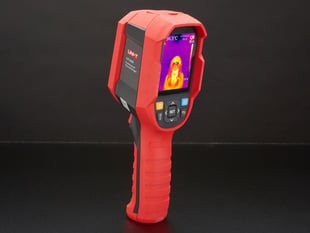 Thermal camera displaying a thermal image on it's lcd screen. Camera is red and grey, with the screen at the top of the camera and a handle at the bottom.