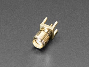 Angled shot of small, metallic, straight coaxial RF connector.