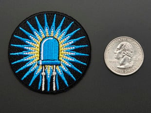 Circular embroidered badge of blue LED with rays of light on black background