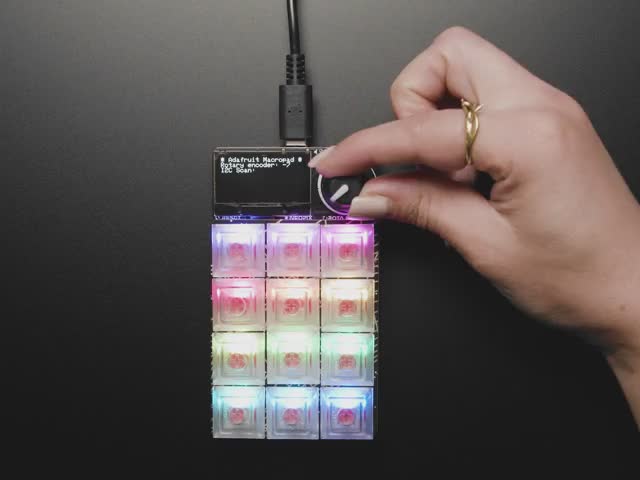 Adafruit MacroPad RP2040 Starter Kit - 3x4 Keys + Encoder + OLED - ADABOX019 Essentials - Video of a hand playing with a rainbow-glowing keypad.