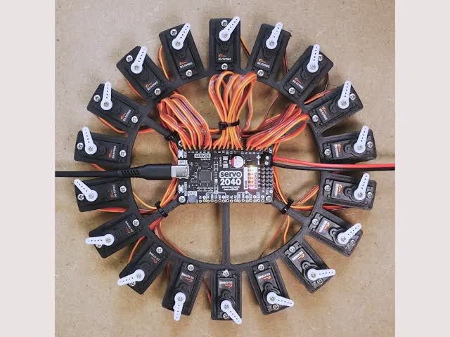 Pimoroni Servo 2040 - RP2040 18 Channel Servo Controller - PIM613 - PIM613 - Top view video of 18 servo motors hooked up to a driver board. The servo motor fans oscillate in order. 