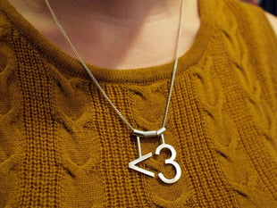 model wearing silver necklace with "<3" heart symbol 