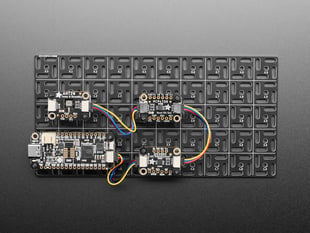 Top shot of a feather, a humidity sensor, a potentiometer and an I2C quad board mounted on to the grid. 