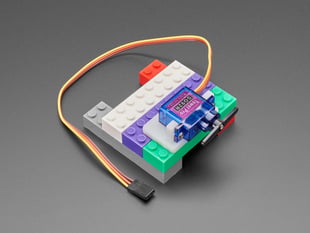 Angled shot of blue micro servo installed in a plastic mount with LEGO bricks.