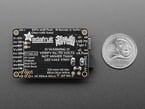 Back of rectangular PCB next to US quarter for scale.