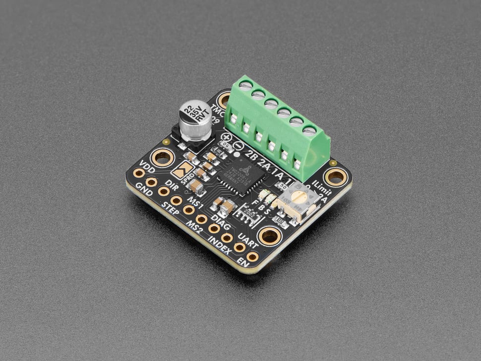 Angled shot of square-shaped motor driver breakout with green terminal blocks.