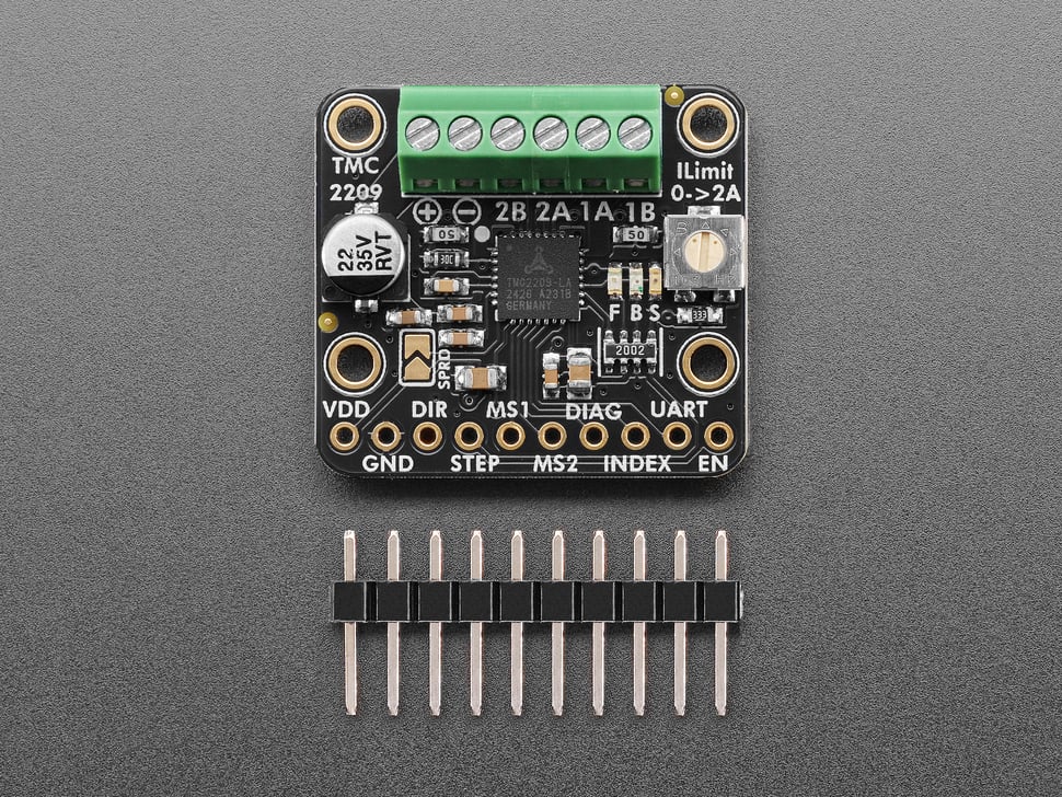 square-shaped motor driver breakout with green terminal blocks above a piece of 10-pin header.