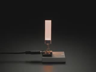 Video of thin and slim, rectangular backlight display plugged into a small breadboard with microcontroller. Backlight display cycles through colors.