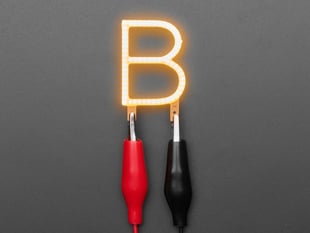 Overhead shot of LED filament in the shape of the letter "B" lit up with alligator clips.