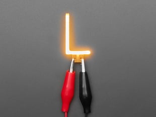 Overhead shot of LED filament in shape of letter "L" lit up with alligator clips.