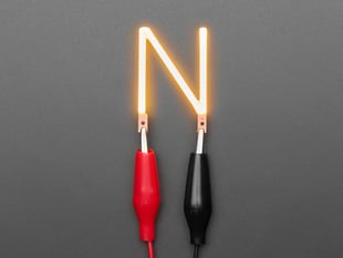 Overhead shot of LED filament in shape of letter "N" lit up with alligator clips.