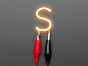 Overhead shot of LED filament in shape of letter "S" lit up with alligator clips.