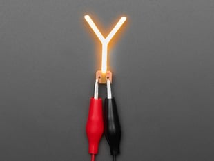 Overhead shot of LED filament in shape of letter "Y" lit up with alligator clips.