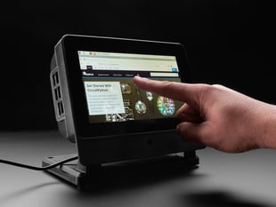 Hand pointing to a touchscreen enclosure.