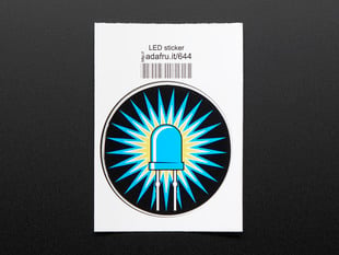 Circular sticker of blue LED with rays of blue light over a yellow corona on black background. Sticker is mounted on white paper with barcode. 