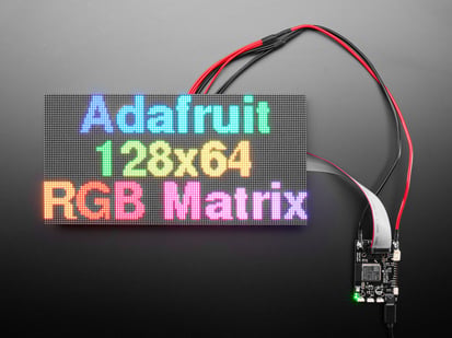 128x64 RGB LED Matrix Panel - 2mm Pitch - LED matrix panel wired up and displaying "Adafruit 128x64 RGB matrix" in rainbow colors.