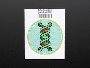 Circular sticker showing a green double helix over an abstracted blue and green circuitboard design. Badge is trimmed in green and mounted on white paper with barcode.  