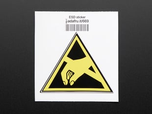Triangle shaped sticker with yellow hand reaching to pick something up, over a black background, with yellow trim. Mounted on white paper with barcode